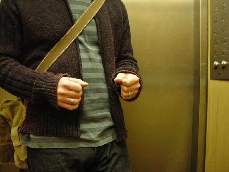 A man nervously clenches his fists inside an elevator.