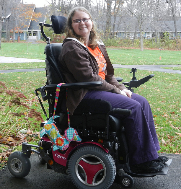 A smiling woman in a motorized wheelchair.