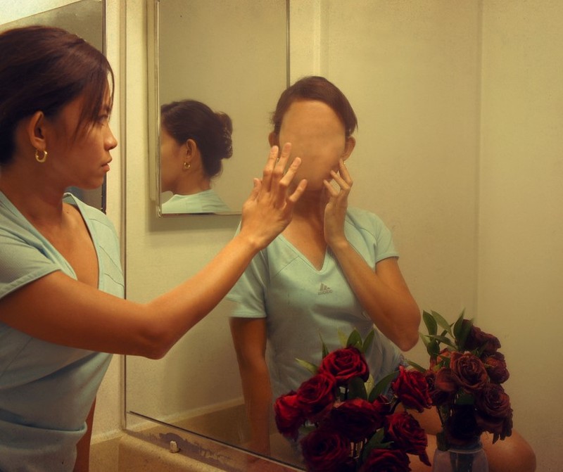 A woman looks into the mirror and sees a faceless reflection.