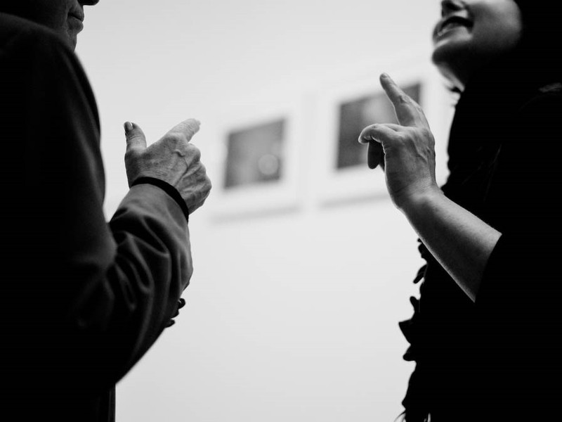 A man and woman are engaged in conversation and making identical hand movements.