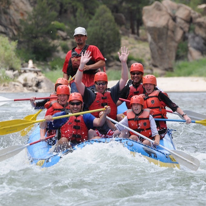 A group of white water rafters paddle together in rough waters.
