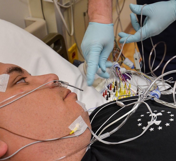 A sleep technician wires a patient for a sleep study.